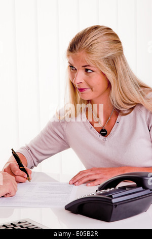 Junge Frau unterzeichnet einen Vertrag in einem Büro, Junge Frau Unterschreibt Einen Vertrag in Einem Buero Stockfoto