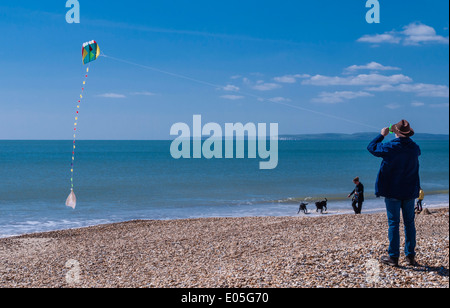 Mann flying a Kite am Strand an der Bucht von Bournemouth, Poole, Dorset, England, UK. Stockfoto