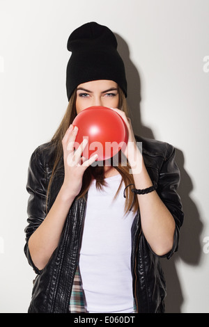 Cute teenage Hipster Mädchen bläst roten Ballon Stockfoto