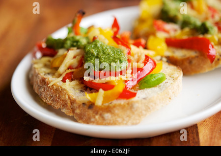 Rote und gelbe Paprikaschote, veganen Käse und hausgemachte Vegan-Basilikum-Pesto auf geröstetem Brot. Stockfoto