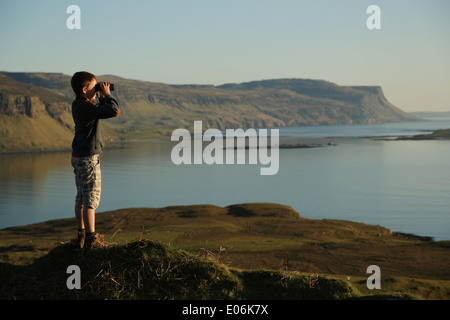 Junge schaut durch ein Fernglas an Ardmeanach Stelle und Loch Na Keal an klaren, blauen Frühlingstag, Isle of Mull, Inneren Hebriden, Schottland Stockfoto