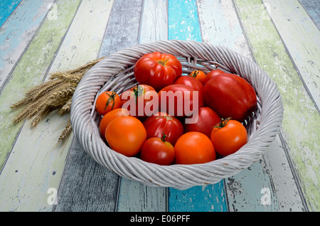 Verschiedene Tomaten in einem Korb auf Holztisch Stockfoto