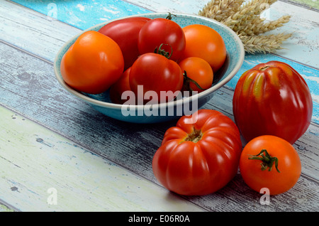 Verschiedene Tomaten in einer Schüssel auf Holztisch Stockfoto