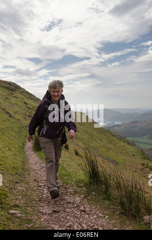 Applying Frau Bergwandern auf Spitze Felsen im englischen Lake District an einem sonnigen frühen Frühlingstag Stockfoto
