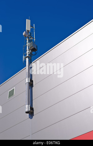 GSM-Antenne. Handy-Signal-Repeater-System installiert auf dem Dach des Industriebaus. Stockfoto