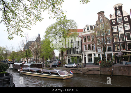 Kanal Boot vorbei an historischen Häusern entlang Prinsengracht Kanal in Amsterdam, Niederlande. Noorderkerk Kirche im Hintergrund. Stockfoto