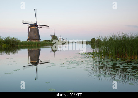 Blick auf fünf Windmühlen und ihre Überlegungen in den umliegenden Gewässern Polder bei Sonnenuntergang, Kinderdijk, Nieuw-Lekkerland, Holland. Stockfoto