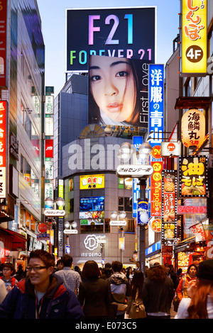 Menschen auf die Straßen von Shibuya beleuchtet hell mit bunten Zeichen abends. Utada Hikaru, erste Liebe und Forever21 billboards Stockfoto