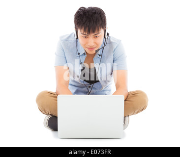 Junger Mann am Boden sitzen und einen Laptop verwenden Stockfoto