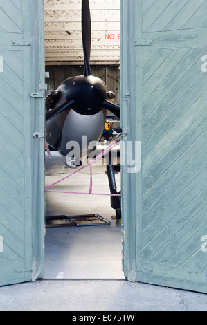 Ein Supermarine Spitfire Jagdflugzeug innen geöffnet teilweise Hangartüren im Geschäft in Duxford Air Museum, England Restaurierung Stockfoto