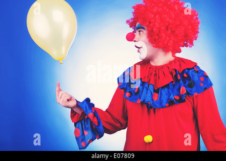 Clown im roten Kostüm mit Ballon getönten Bild auf blauem Hintergrund. Studio shooting Stockfoto