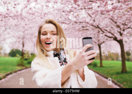 Glückliche junge Frau selbst mit ihrem Handy zu fotografieren. Kaukasischen Frauen sprechen Selfie mit ihrem Smartphone im Park. Stockfoto