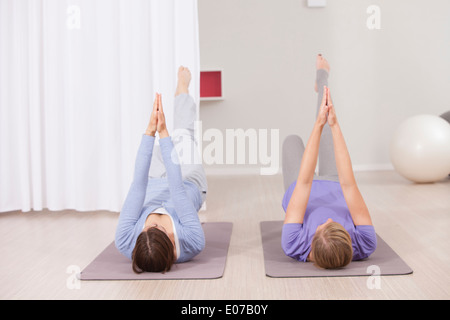Frauen, die Pilates-Übung mit gefalteten Händen Stockfoto