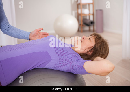 Ältere Frau auf Gymnastikball erhalten Physiotherapie Stockfoto