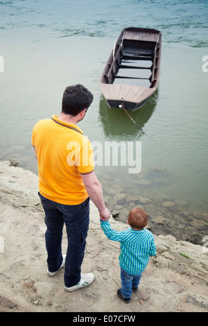 Vater und Sohn am Ufer betrachten Boot, Österreich Stockfoto