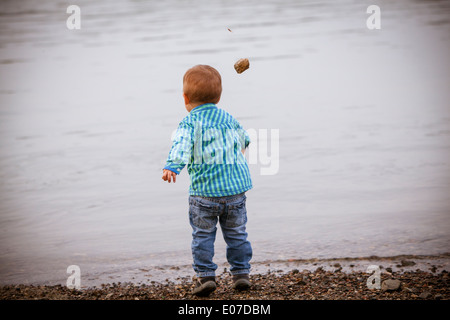 Kleinkind Jungen Steinwürfe in einem See, Österreich Stockfoto