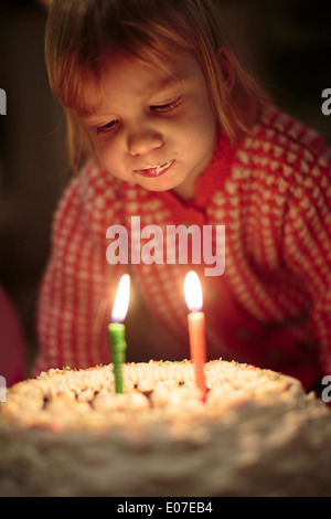 Kleines Mädchen bläst Geburtstagskerzen auf Kuchen Stockfoto