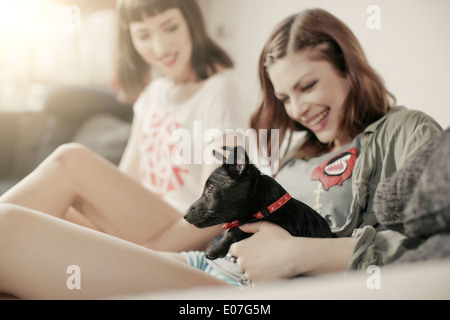 Zwei junge Frauen spielen mit Hund Stockfoto