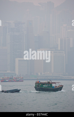 Nebel im Victoria Harbour, Sampan schleppt ein kleines Fischerboot durch Victoria Harbour für die Tage Arbeit. Stockfoto