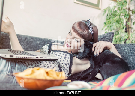 Junge Frau mit Laptop neben ihrem Haustier Hund Stockfoto