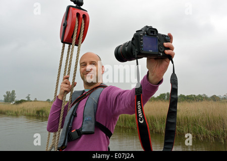 Fotograf, wobei ein Selbstporträt mit einer SLR-Kamera mit Zoom-Objektiv an Bord der historischen Norfolk Wherry Albion, Broads National Park Stockfoto