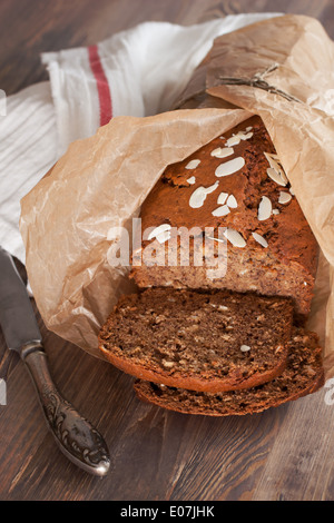 Frisch gebackenes Bananenbrot mit Mandeln in Backpapier auf das Holz Stockfoto