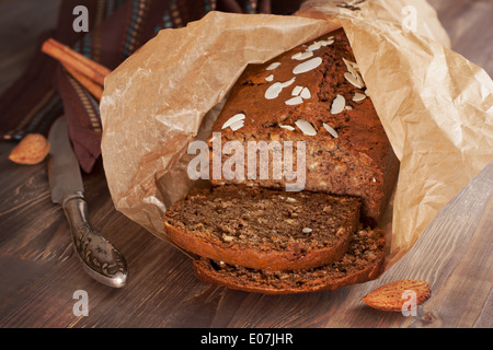 Frisch gebackene Bananenbrot mit Mandeln, Zimt und in Backpapier auf das Holz Stockfoto