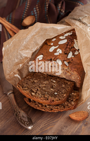 Frisch gebackene Bananenbrot mit Mandeln, Zimt und in Backpapier auf das Holz Stockfoto