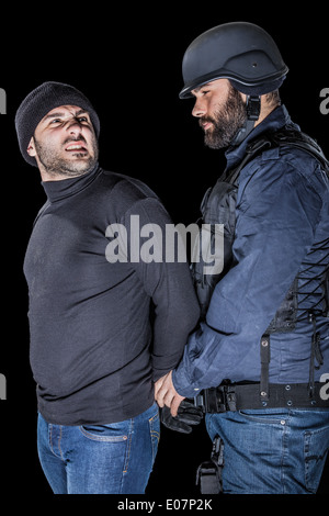 ein Polizist mit dem SWAT taktische Weste verhaften einen Einbrecher Stockfoto