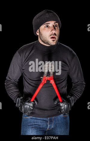 ein Einbrecher tragen schwarze Kleidung mit riesigen Drahtschneider auf schwarzem Hintergrund Stockfoto