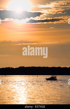 Bewölkten Sonnenuntergang mit Silhouette der einsame Boot Stockfoto
