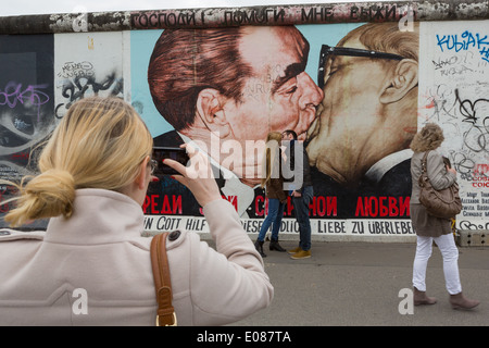 Ein paar Kuss vor Dimitry Vrubel Gemälde auf der Berliner Mauer von Leonid Brezhnev und Erich Honecker Stockfoto