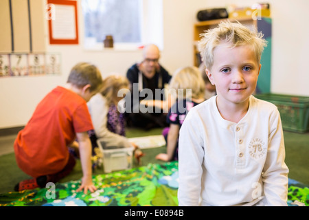 Porträt eines jungen mit Lehrer und Mitschülern im Hintergrund im kindergarten Stockfoto