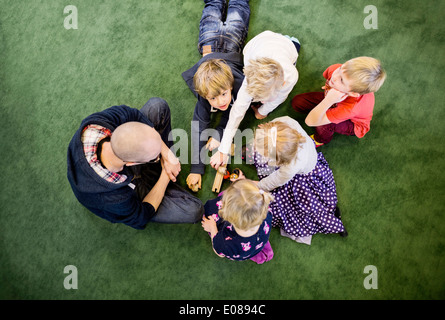 Direkt über dem Schuss von Lehrer mit Schülern auf Teppich im Kindergarten spielen Stockfoto