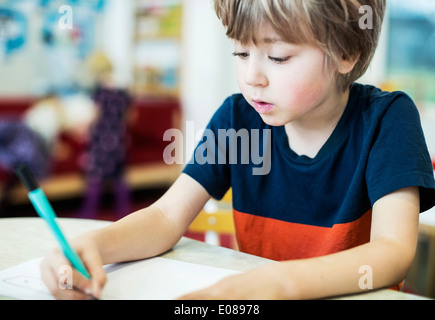 Junge, Zeichnung auf Papier am Tisch im kindergarten Stockfoto