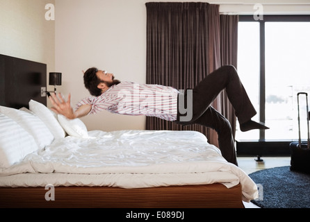 Gesamte Länge der Geschäftsmann springen auf Bett im Hotelzimmer Stockfoto