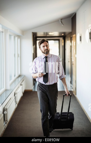 Geschäftsmann mit Koffer zu Fuß im Hotelflur Stockfoto