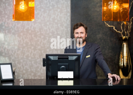 Porträt von zuversichtlich männliche Angestellte an der Rezeption stehen am Schalter im hotel Stockfoto