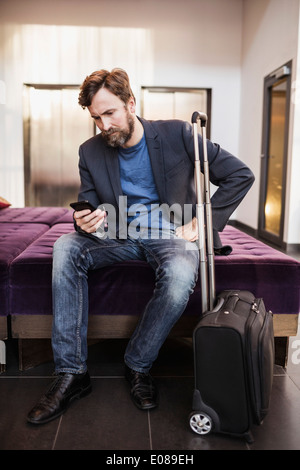 Geschäftsmann mit Handy in der Hotellobby Stockfoto