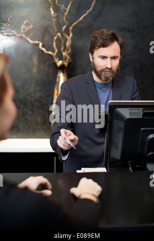 Männliche Angestellte an der Rezeption akzeptieren Zahlung per Kreditkarte vom Kunden im hotel Stockfoto