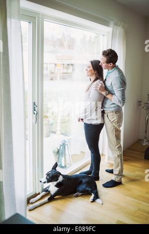 Seitenansicht des Paares Blick durch Fenster zu Hause Stockfoto