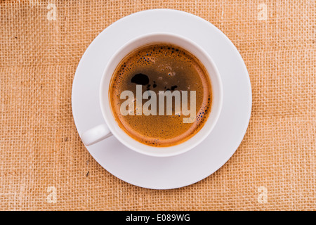 Weiße Kaffeetasse mit frischen heißen Kaffee auf Leinwand. Ansicht von oben. Stockfoto