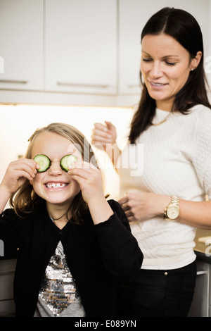 Mutter Tochter Abdeckung Augen betrachten, mit Gurkenscheiben Stockfoto