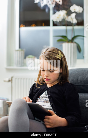 Mädchen mit digital-Tablette auf Sofa im Wohnzimmer Stockfoto