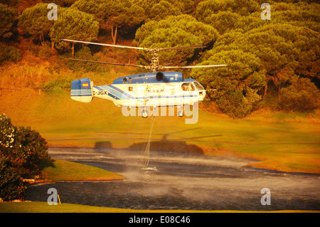 Kamov Ka-32A11BC Hubschrauber (Registrierung EG-JSQ) sammeln Wasser zur Brandbekämpfung von einem Golfplatz See Cabopino Golf. Stockfoto