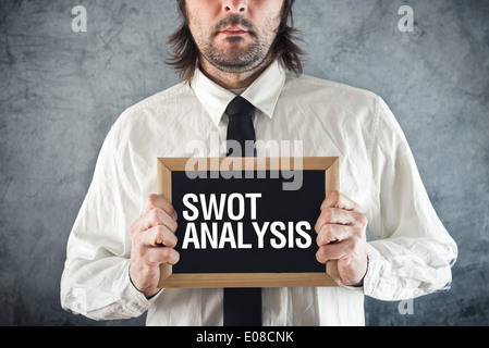 Businessman holding blackboard with SWOT ANALYSIS title. Business analyzing concept. Stockfoto