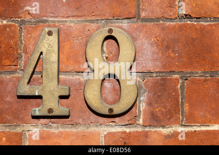 Metall-Nummer 48 an einer Mauer befestigt. Stockfoto