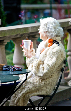 Gut gekleidete Dame sitzen in der Sonne, Bryant Park New York City. Stockfoto