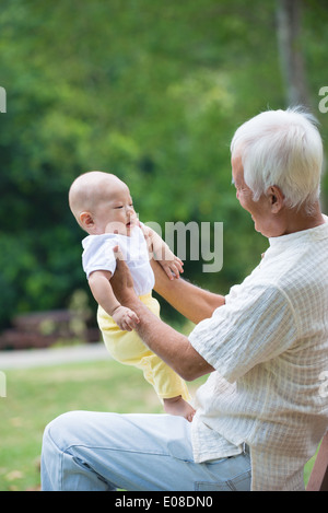 asiatische Großeltern spielen mit Baby Enkel im Außenbereich Stockfoto