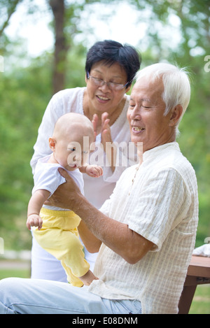 asiatische Großeltern spielen mit Baby Enkel im Außenbereich Stockfoto